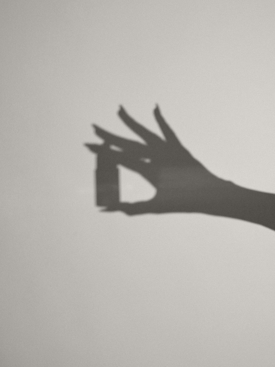 Image of shadow with hand holding the Aleph Serum Primer